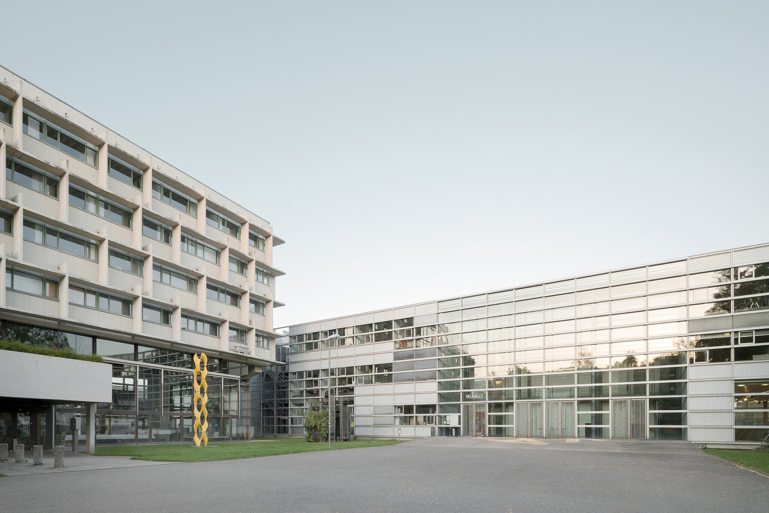 Zwei moderne, mehrstöckige Gebäude mit Glas- und Betonfassade.